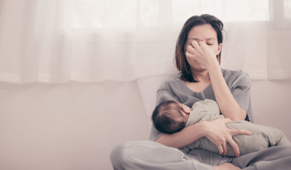 image of a woman holding a baby looking stressed, suffering from PPD