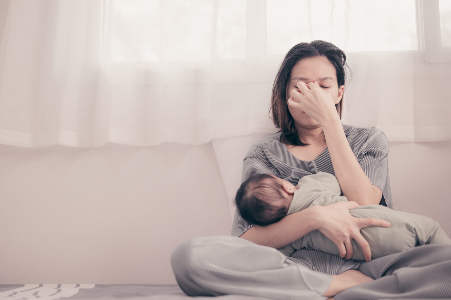 image of a woman holding a baby looking stressed, suffering from PPD