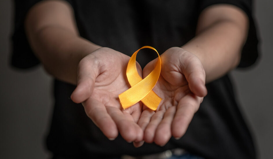 Hands hold yellow ribbon. Concept of suicide problems and their prevention