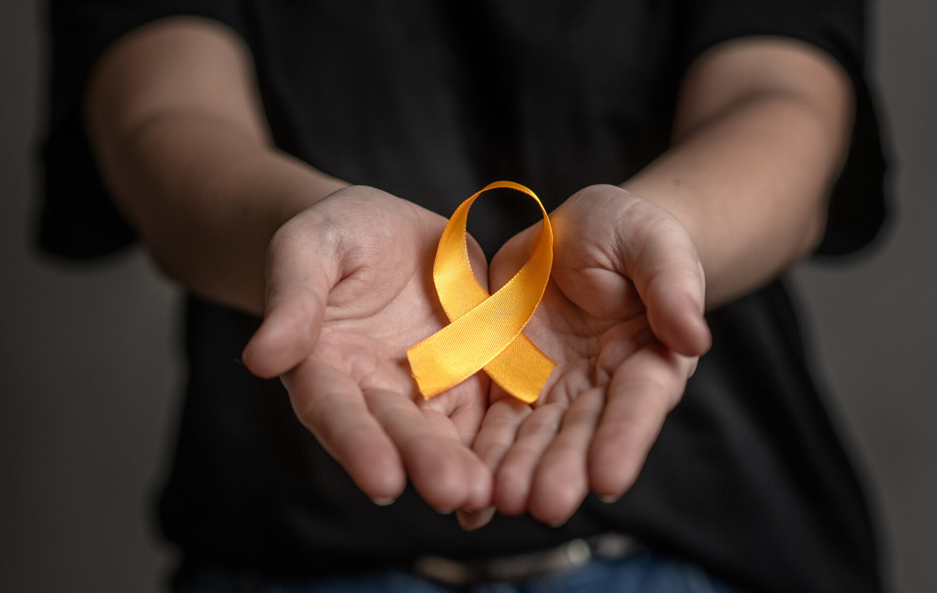 Hands hold yellow ribbon. Concept of suicide problems and their prevention