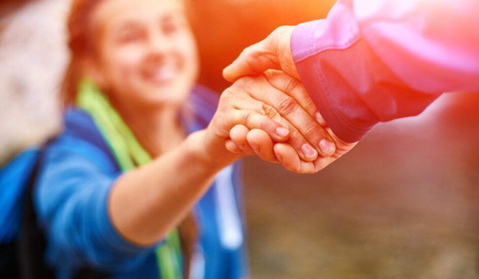 Helping hand: a person reaching out to another on a hike, offering support.